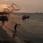 A man casts a fishing net in the sunset.